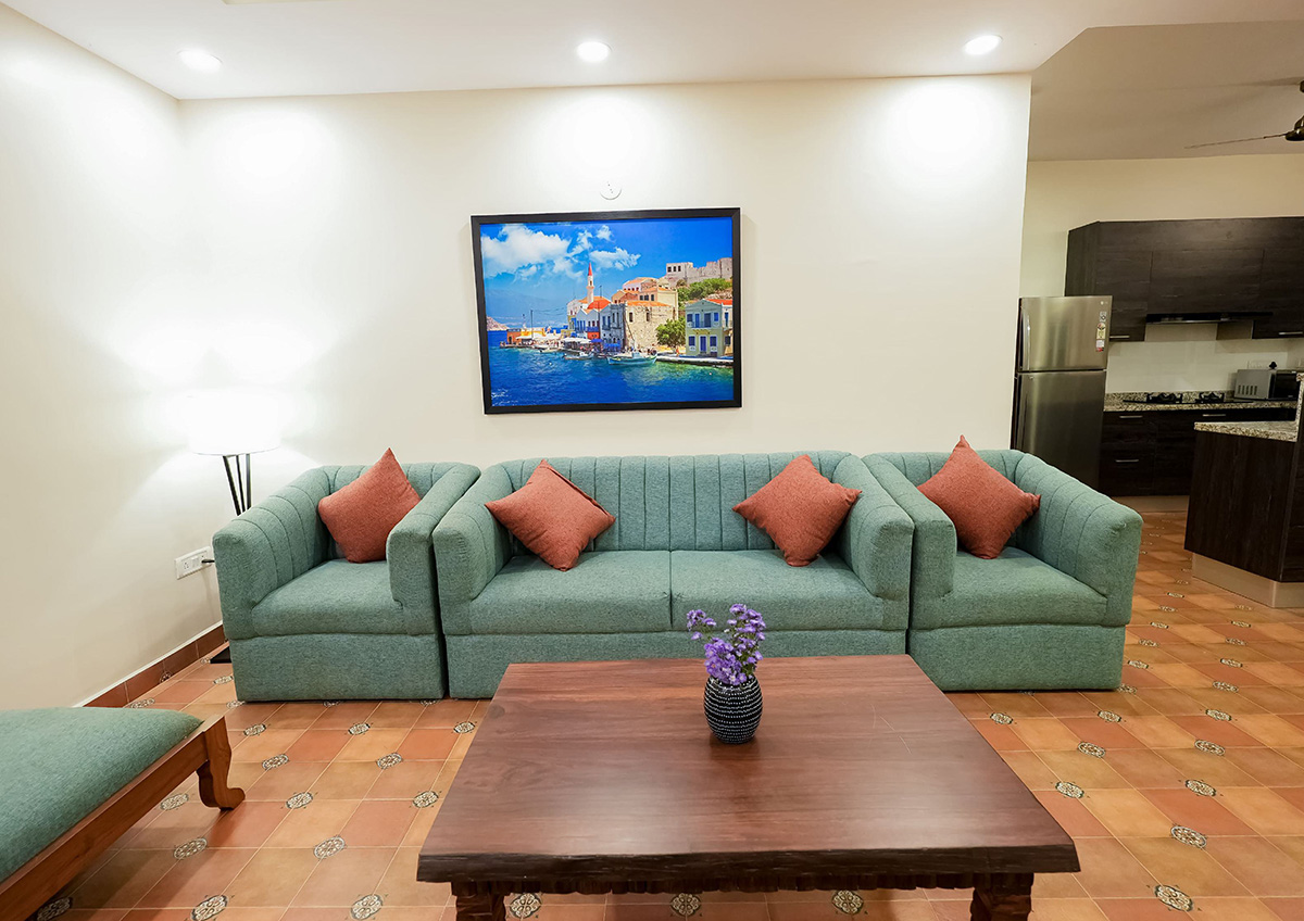 Living room with green sofa, decorative cushions, and wall painting