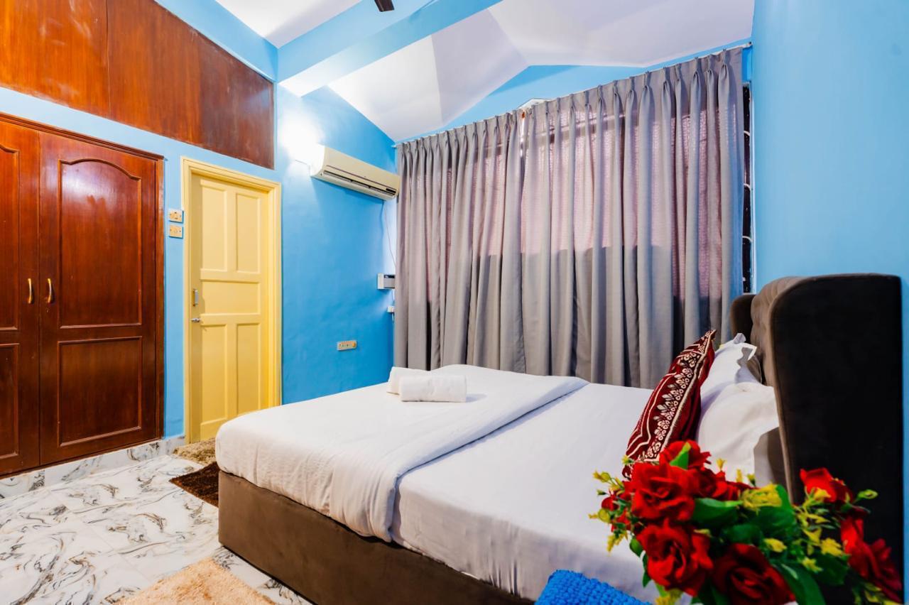 Blue bedroom, bed with brown headboard, AC unit, gray curtains, yellow door.