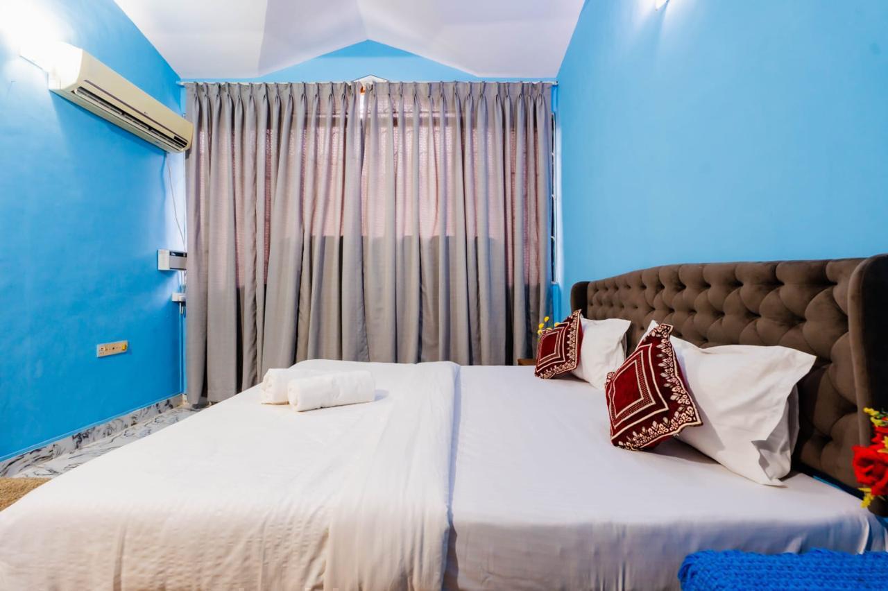 Blue bedroom with large bed, AC, gray curtains, and modern ceiling fan.
