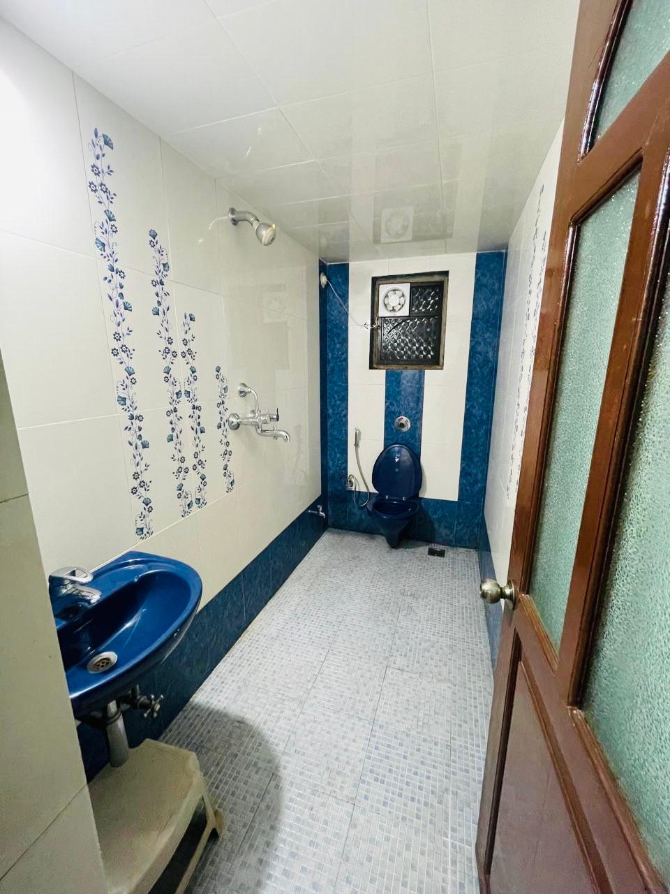 Bathroom with blue and white patterned tile and a blue toilet