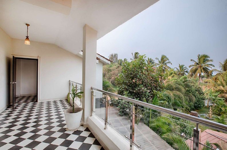 Villa balcony with glass railing overlooking palm trees and greenery