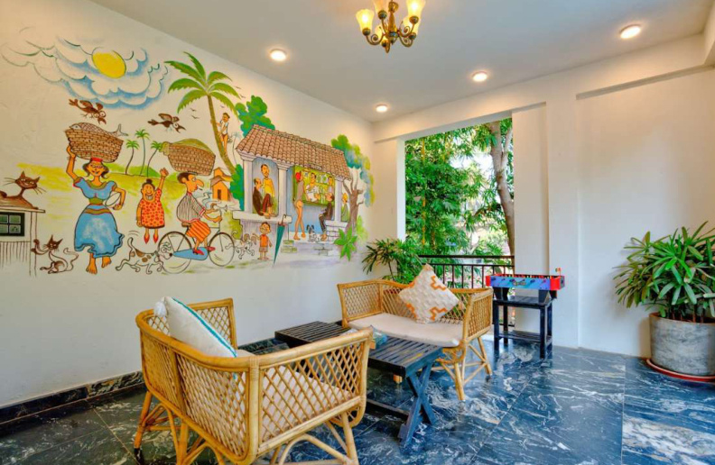 Stylish villa lounge with rattan seating and traditional Goa mural painting