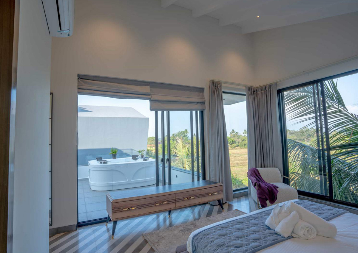 Spacious bedroom opening to balcony with large windows and countryside views