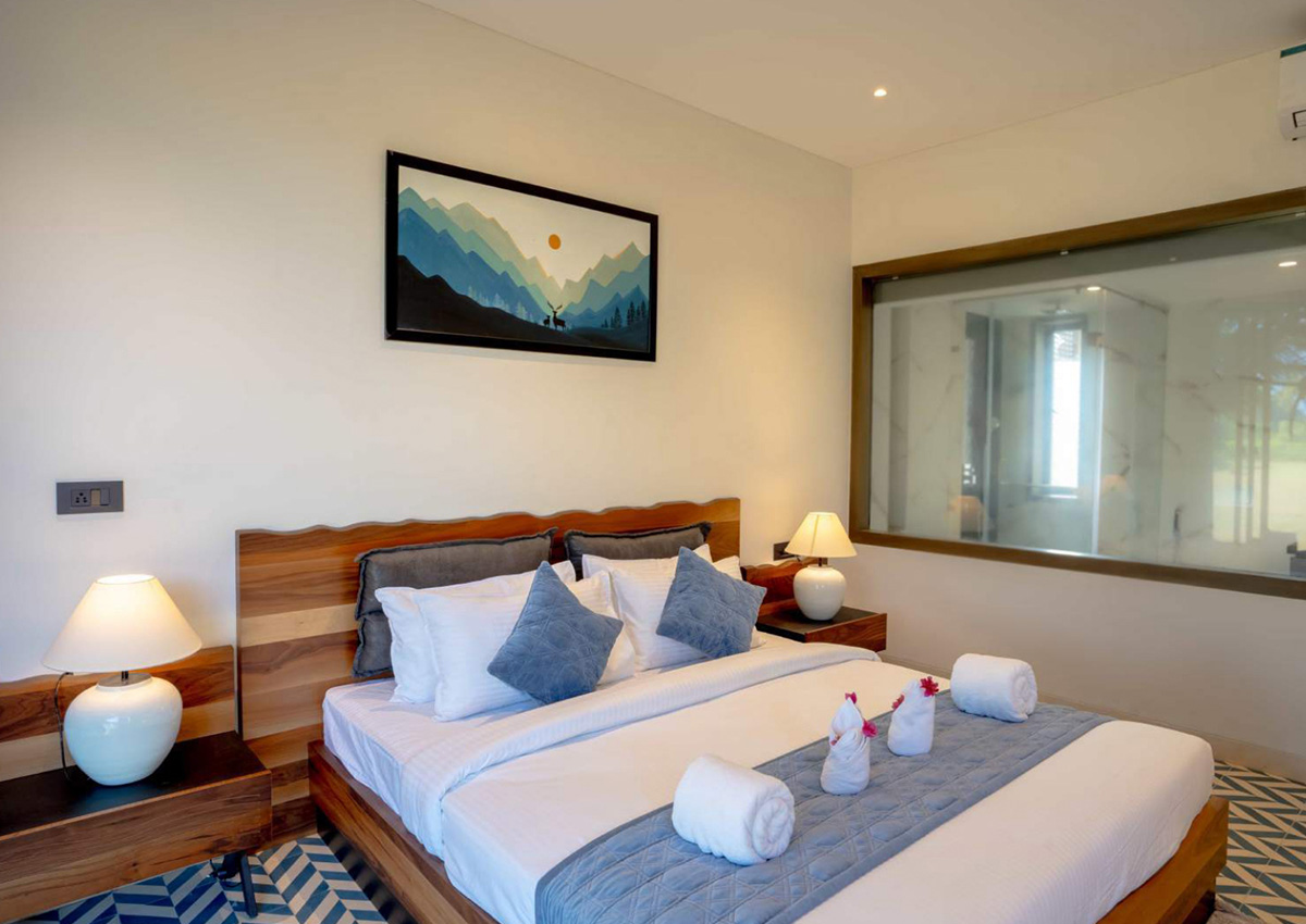 Bedside angle of blue-themed room showing wooden nightstand, lamp, and soft textiles