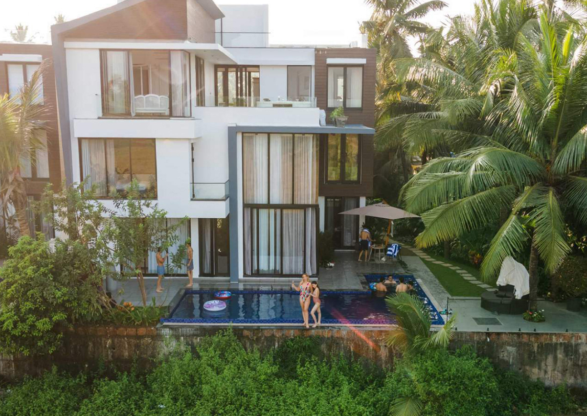 Luxury villa exterior with poolside seating and guests enjoying the water