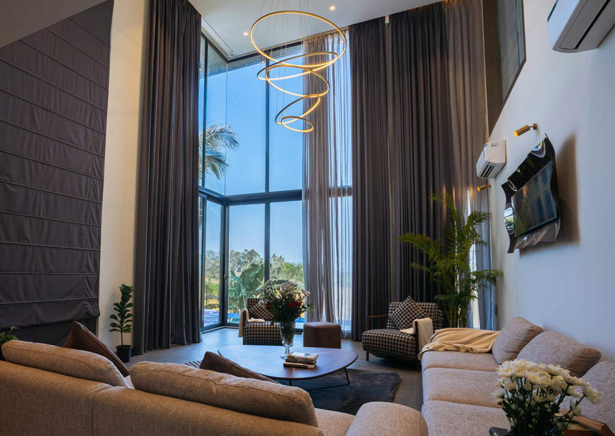 Living room with tall sheer curtains, modern chandelier, and plush sofas