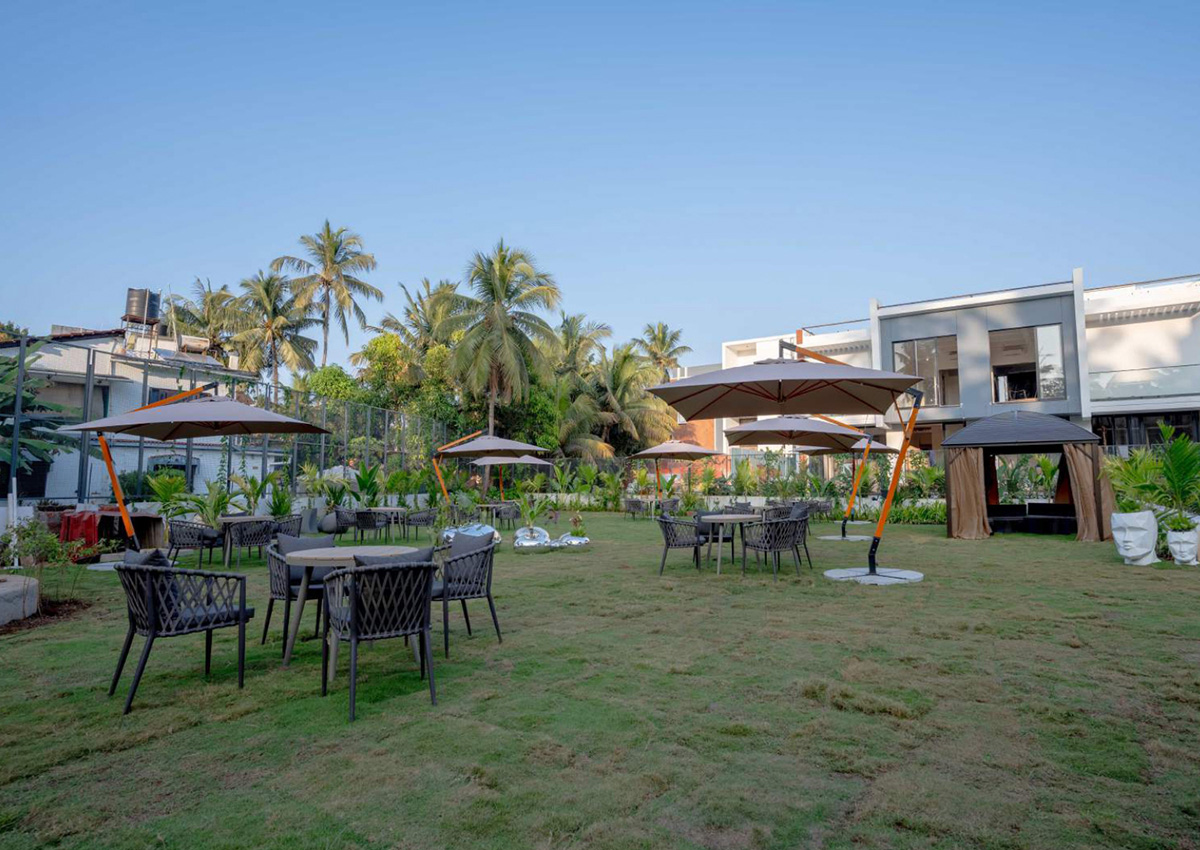 Outdoor lawn area with seating, umbrellas, and lush tropical landscaping